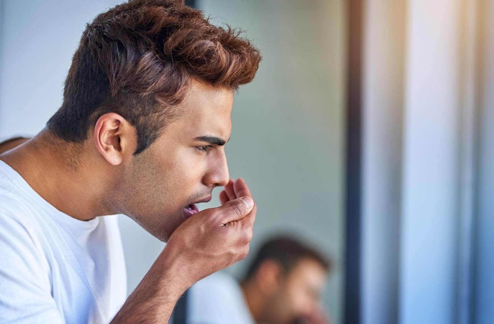 An adult blows into their cupped hand to test the smell of their breath.