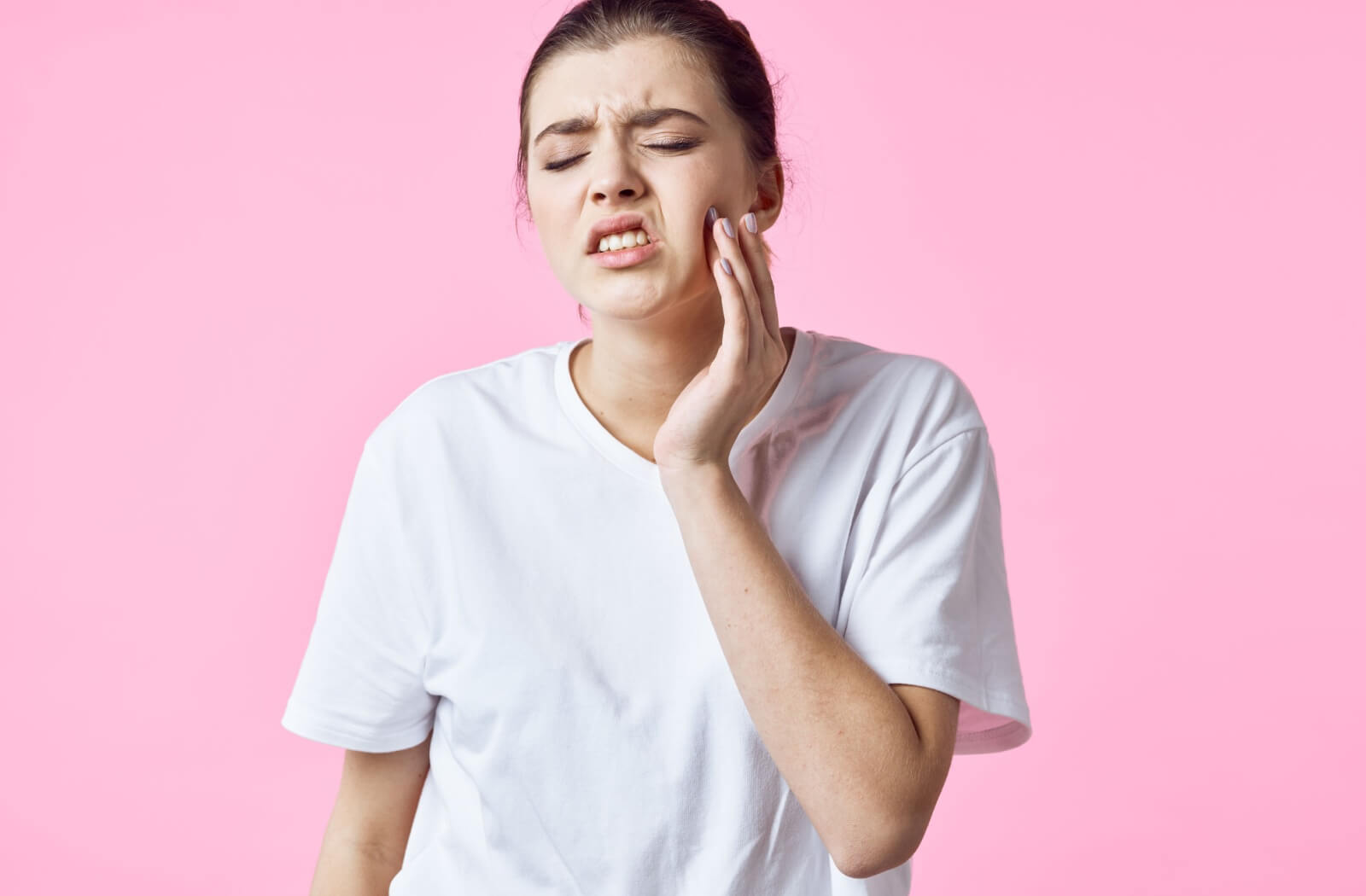 A young person holds the side of their face in pain from a tooth infection.